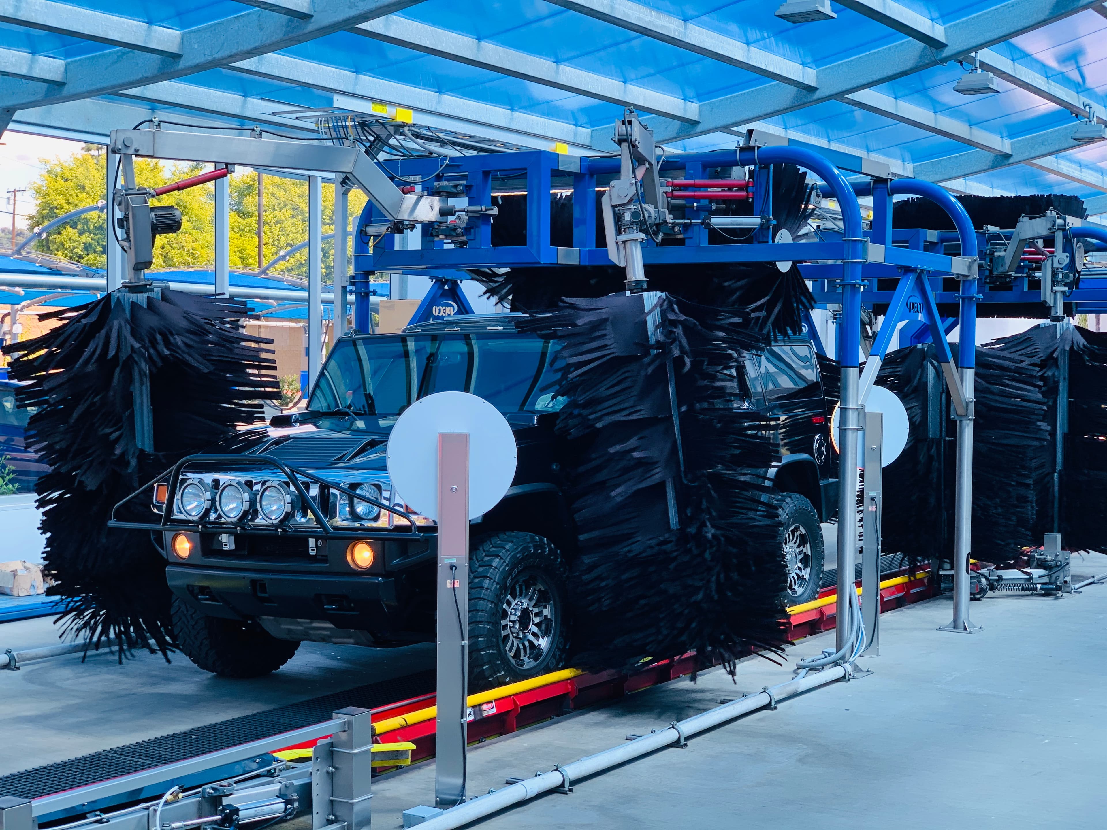 A vehicle moving through Buff-N-Shine's dry polish tunnel with black polishing brushes